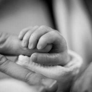 Close-up of a newborn's hand gently holding an adult's finger, symbolizing love and connection.